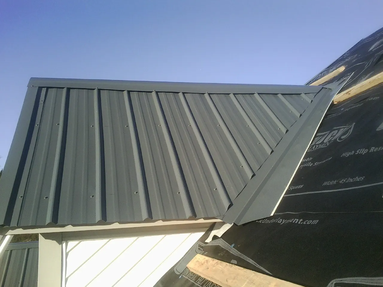 Gray metal roof panels going on over a garage gable in Stanton