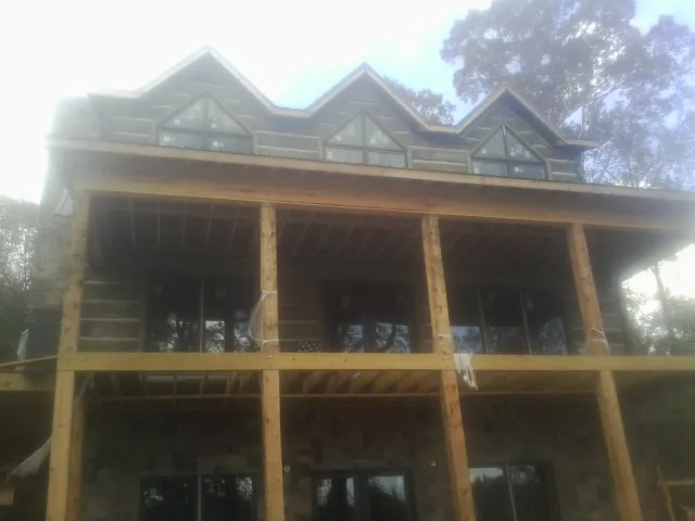 Dormers and porch framing on a large log home under construction — Roof Coating work by our crew in Stanton