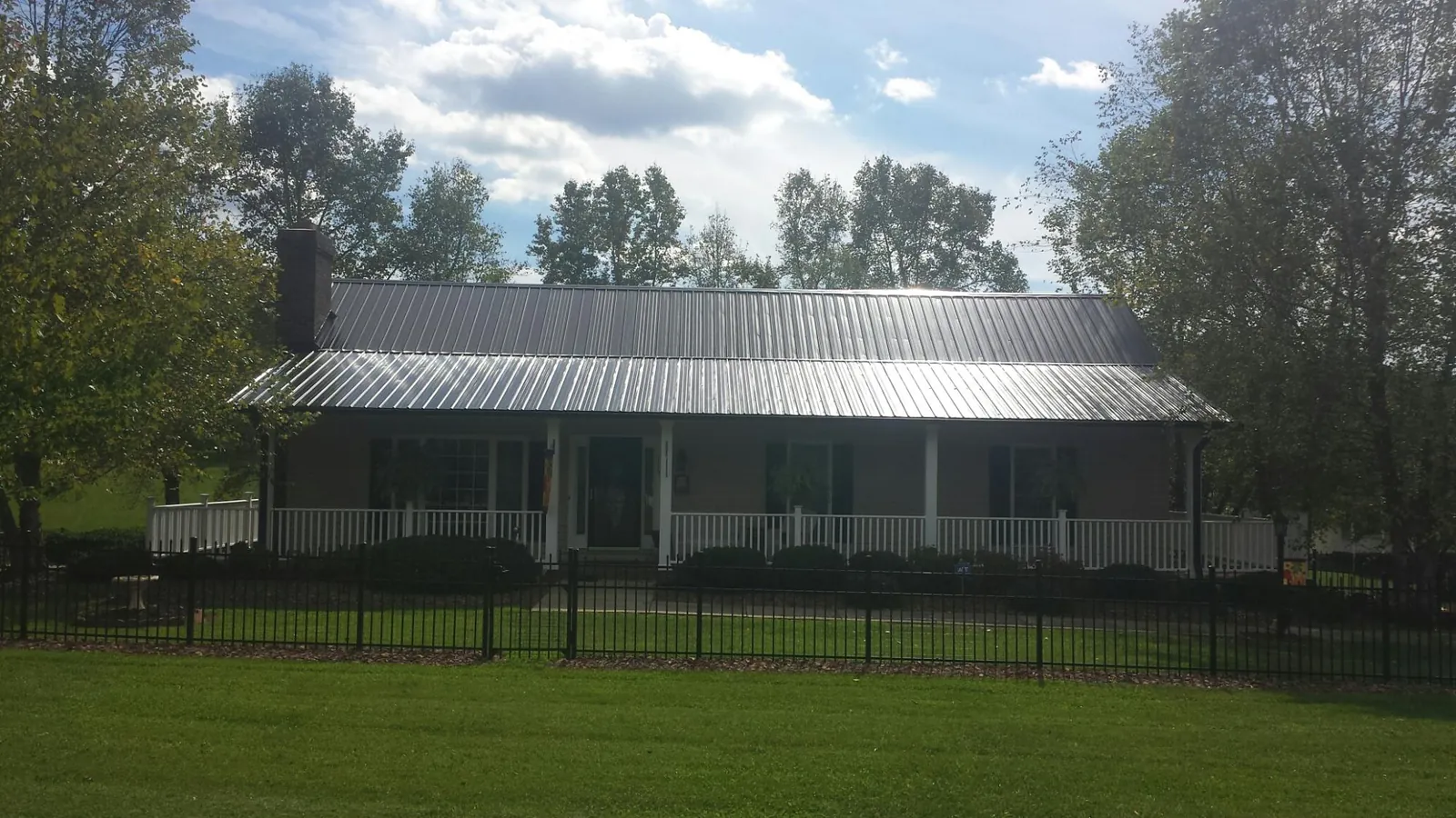 Gray metal roof on a brick ranch with a full width front porch — Gutter Guard Installation work by our crew in Stanton